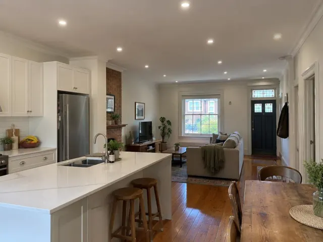 Open-plan kitchen and living room with recessed downlights in a painted home interior in Kingsford
